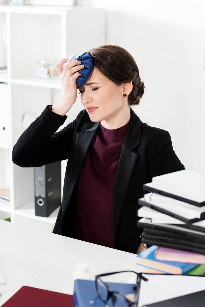 donna d'affari malsana toccare la testa con impacco di ghiaccio in ufficio
 - Foto, immagini