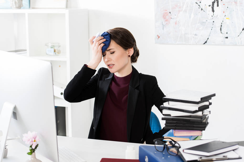 donna d'affari con mal di testa e testa commovente con impacco di ghiaccio in ufficio
 - Foto, immagini