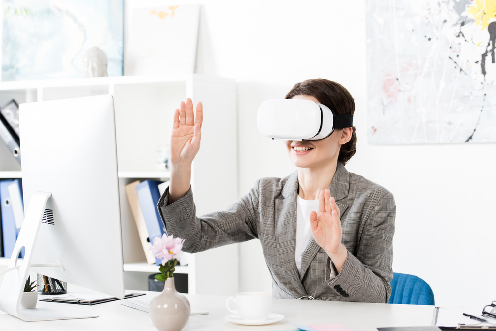 Mujer de negocios sonriente usando auriculares de realidad virtual en la oficina
 - Foto, imagen
