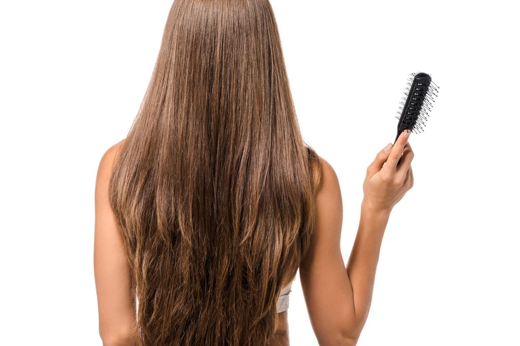 back view of girl with long brown hair holding hairbrush isolated on white - Photo, Image