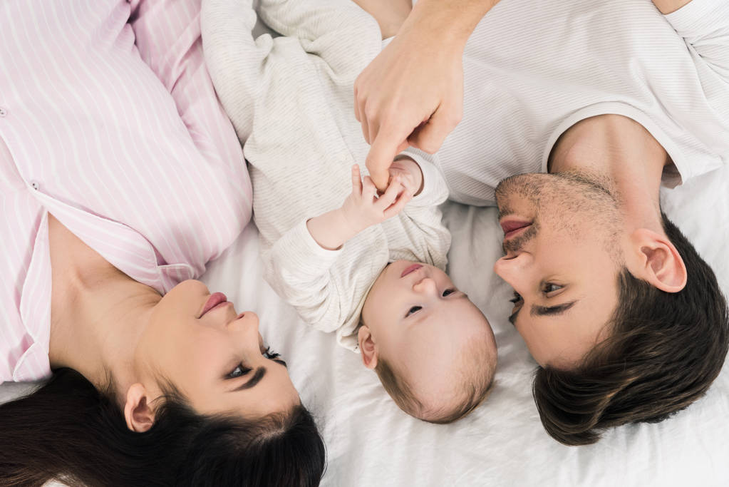 mutlu bir aile ile birlikte yatakta yatarken bebek havai görünümü - Fotoğraf, Görsel