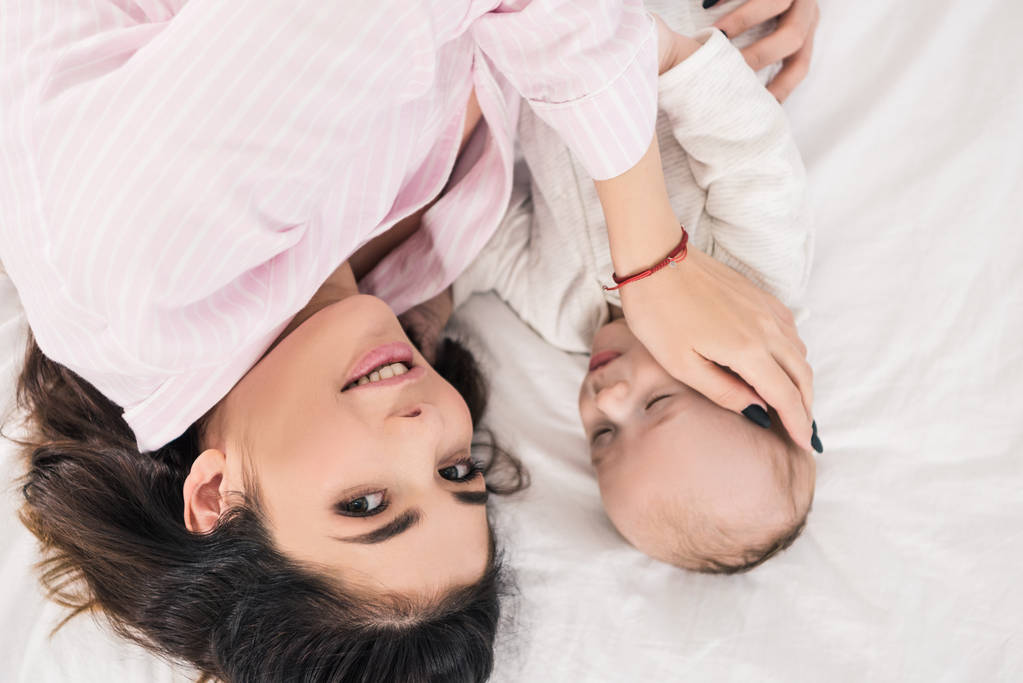 vista aérea de la madre y el pequeño hijo acostados en la cama juntos
 - Foto, Imagen