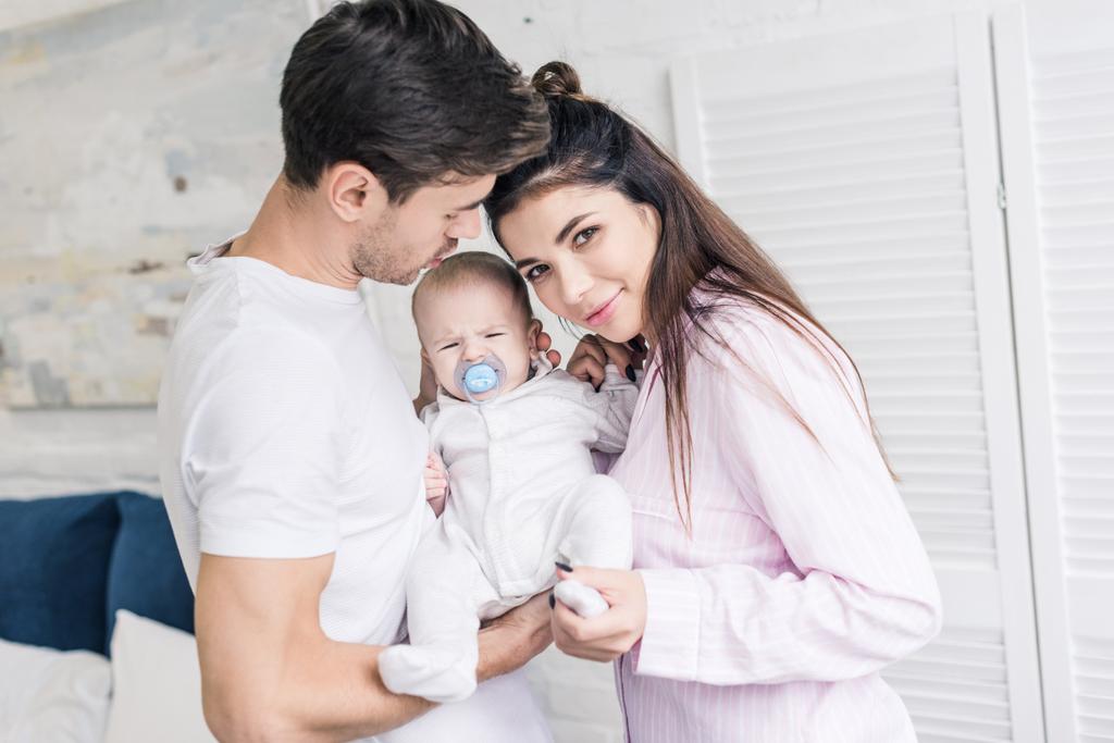 portré, fiatal szülők és az aranyos kis baba a cumit otthon - Fotó, kép