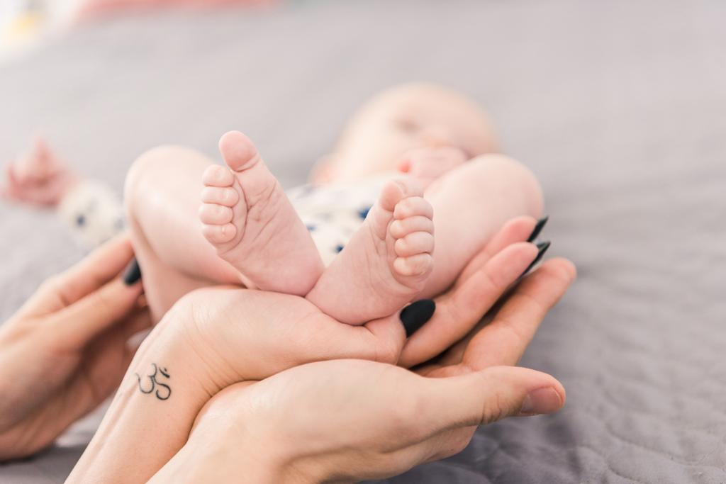 partial view of mother and father holding babys feet together - Photo, Image