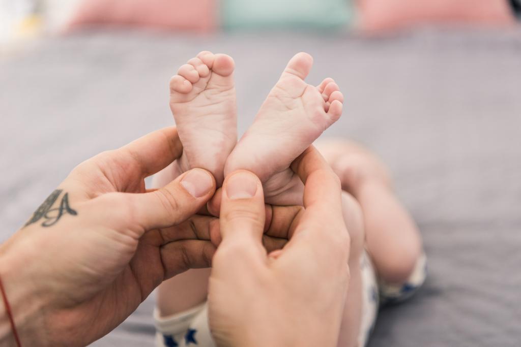 tiro cortado de pai segurando pequenos filhos pés em mãos
 - Foto, Imagem