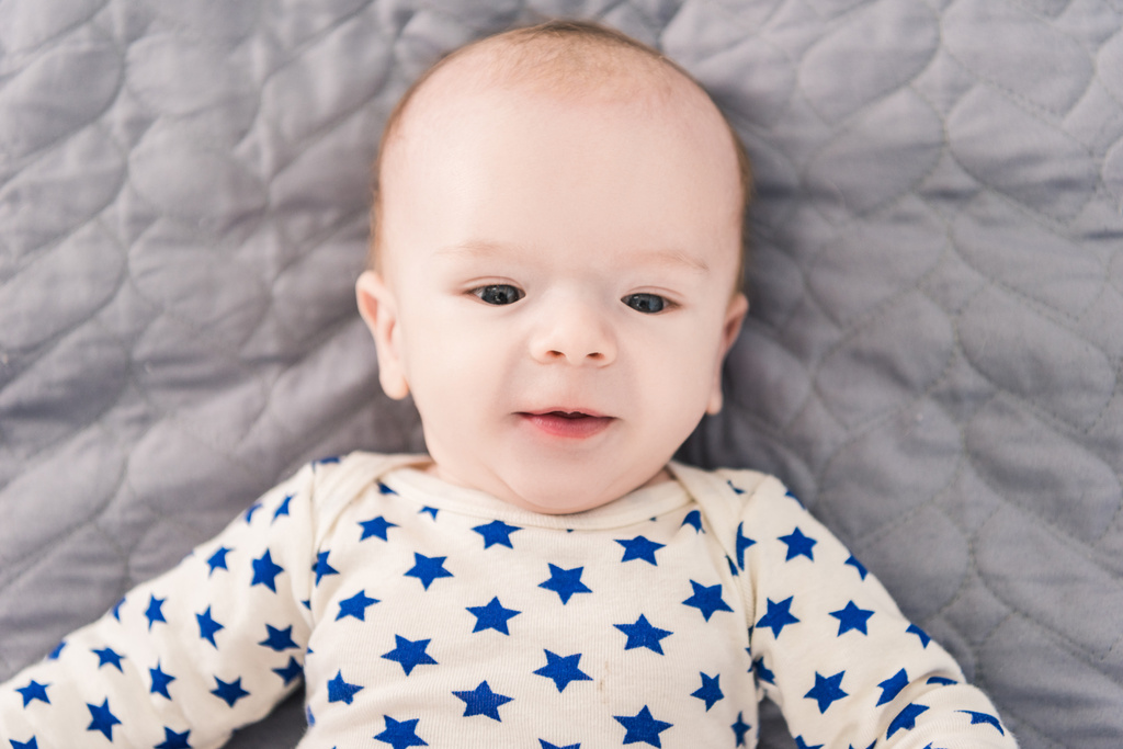 灰色の毛布の上に横たわる愛らしい赤ちゃんのオーバー ヘッド ビュー - 写真・画像