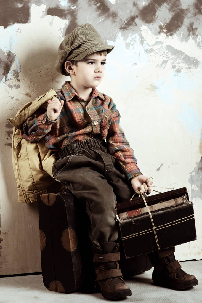 Menino sentado na bagagem segurando livros, retro estilizado tiro, 50s-60s
 - Foto, Imagem