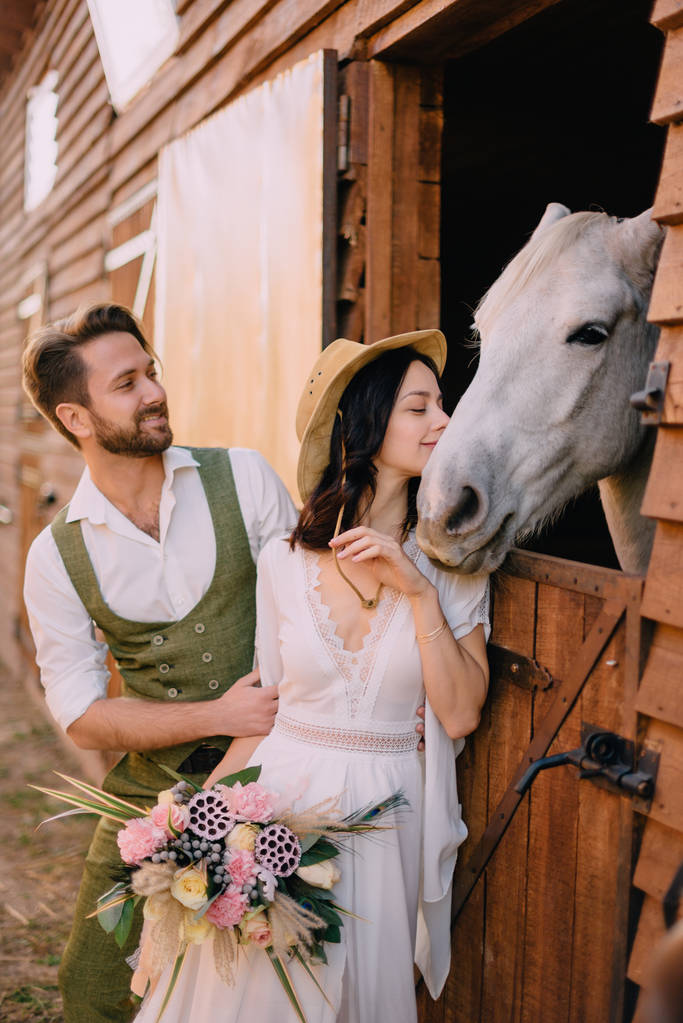 馬、カントリー スタイルの近くを抱いてスタイリッシュな新婚夫婦 - 写真・画像