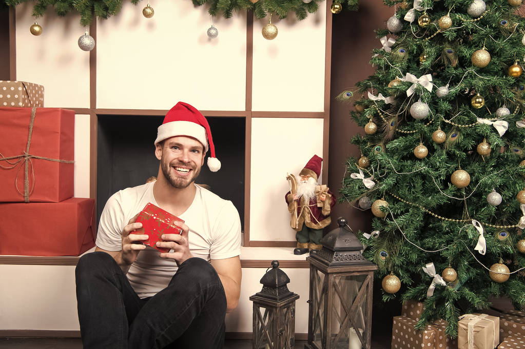 Macho sonrisa con caja de regalo en el árbol de Navidad
 - Foto, Imagen