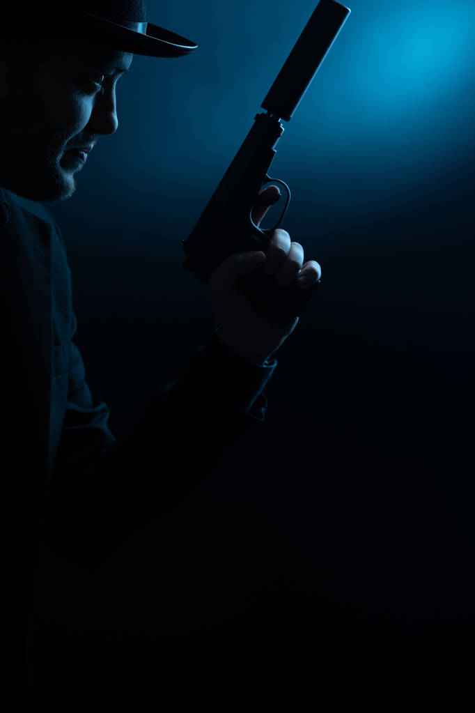 Ritratto di lato dell'uomo in cappello nero con pistola
 - Foto, immagini