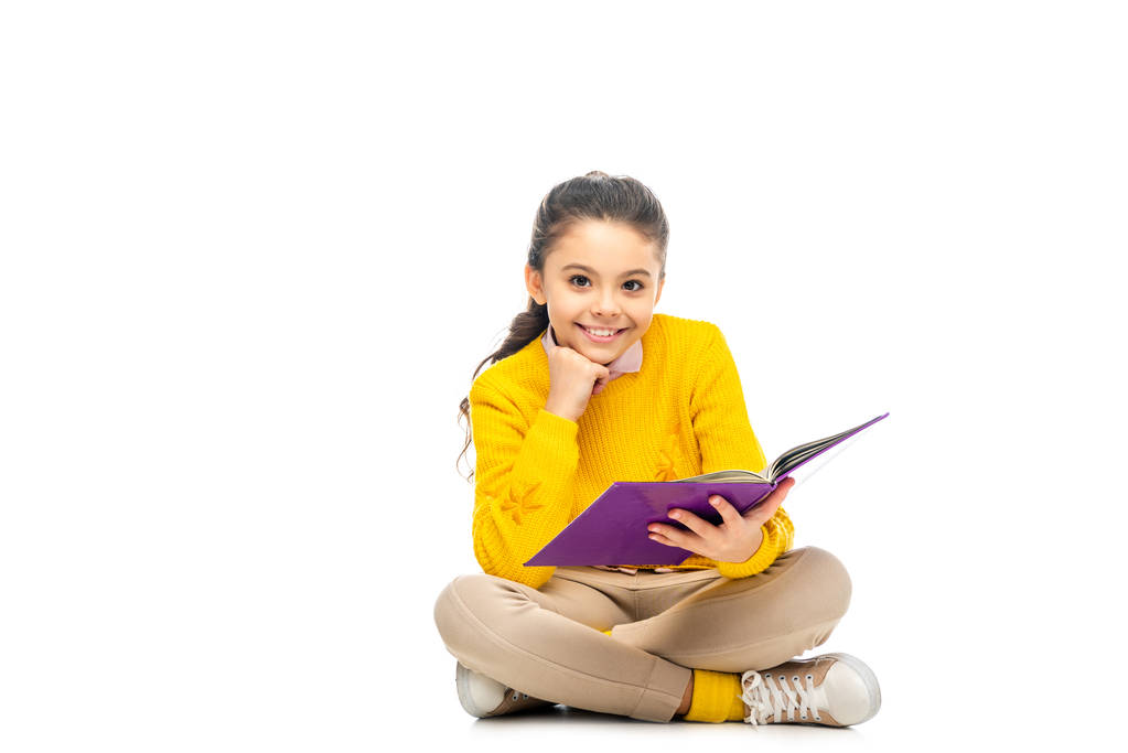 uczennica uśmiechający się w żółty sweterek prowadzące księgę fioletowy i patrząc na kamery na białym tle - Zdjęcie, obraz