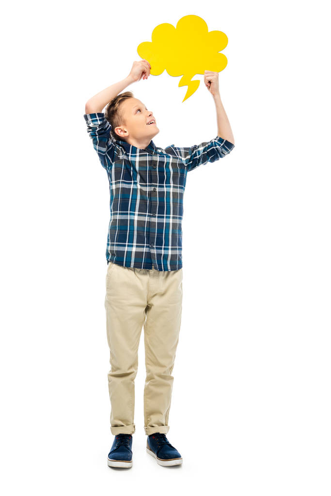 niño sonriente mirando burbuja de habla amarilla sobre la cabeza aislado en blanco
 - Foto, Imagen