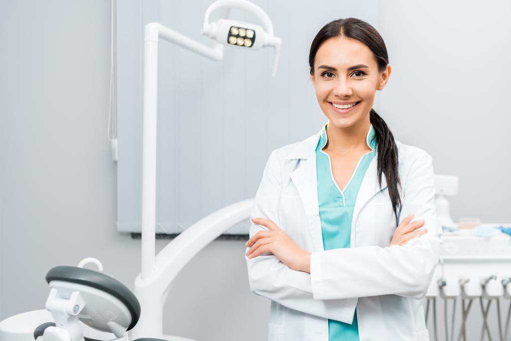 beautiful dentist standing with crossed arms in dental clinic - Photo, Image
