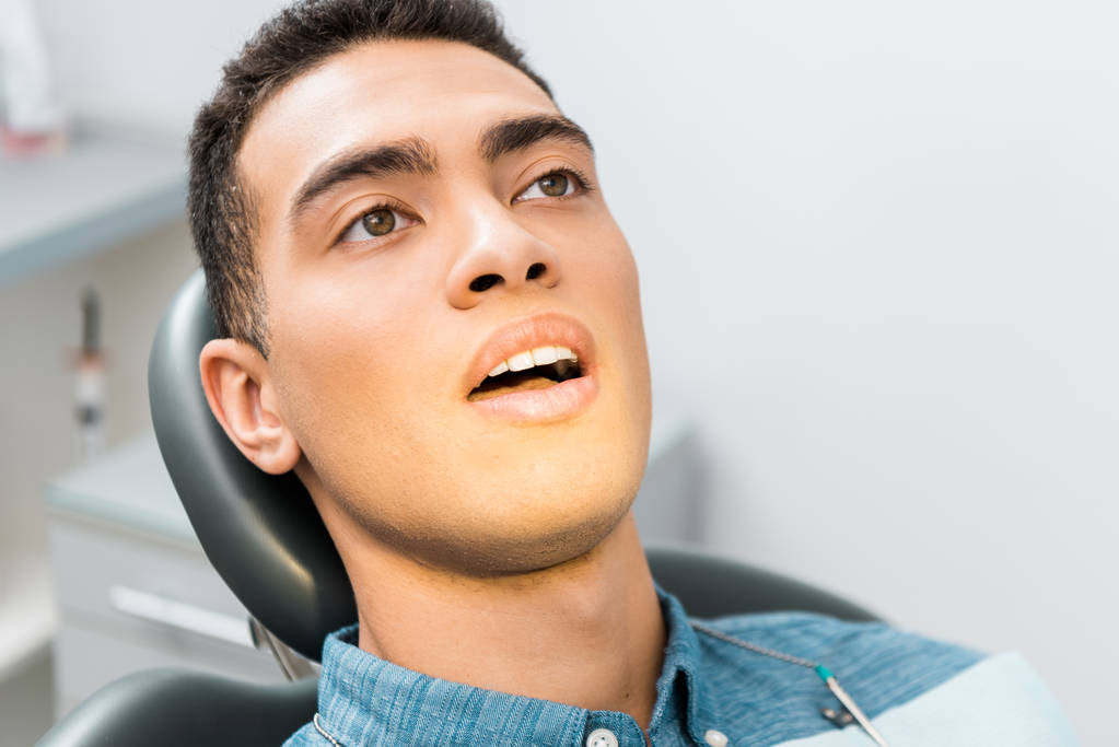 zbliżenie na przystojny mężczyzna african american z otwartymi ustami w klinice stomatologicznej  - Zdjęcie, obraz