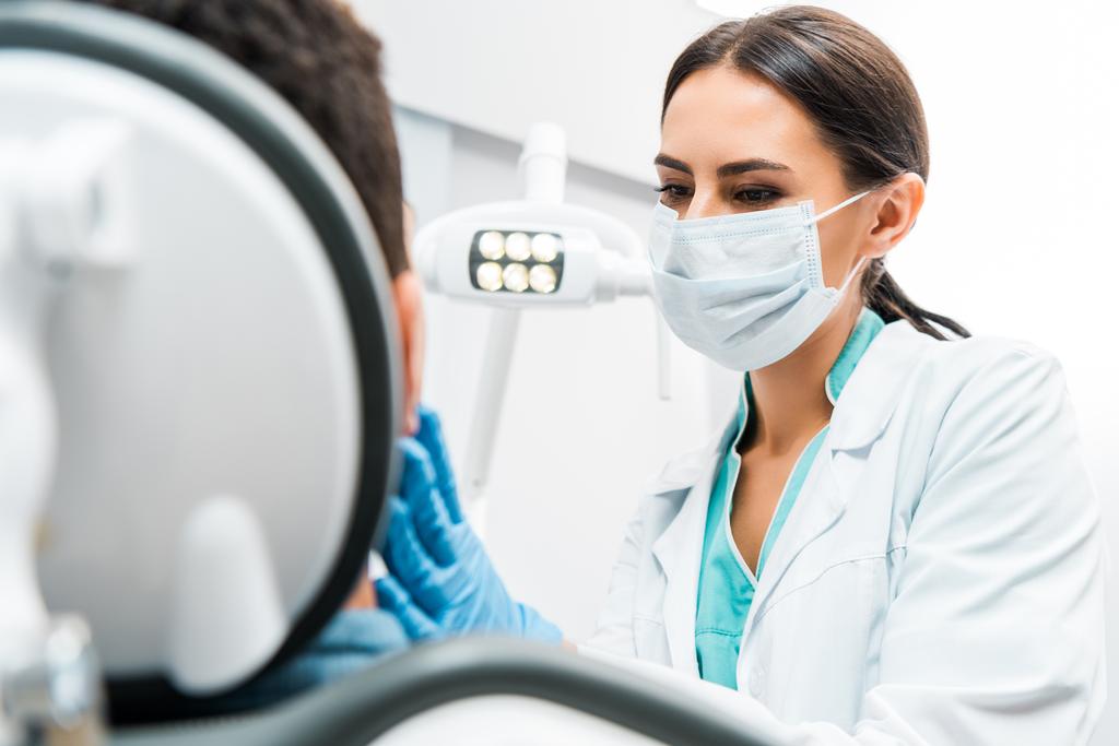 Zahnärztin in Maske untersucht Patientin  - Foto, Bild