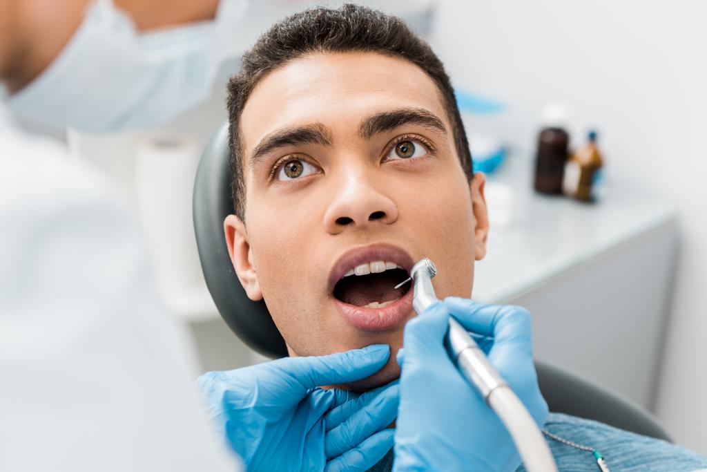 Close up van tandarts boren tanden van Afro-Amerikaanse man  - Foto, afbeelding