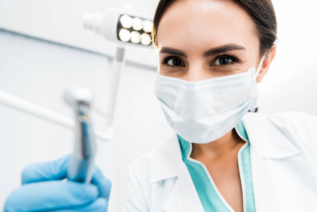 επιλεκτική εστίαση της γυναικείας οδοντίατρος κρατώντας στο χέρι το τρυπάνι  - Φωτογραφία, εικόνα