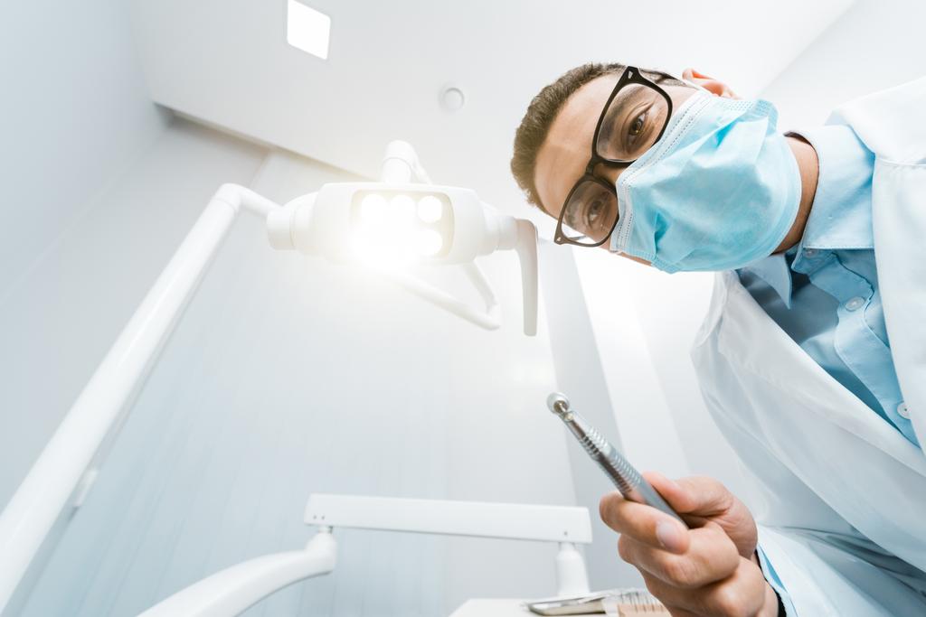 Afryki amerykański dentysta w biały płaszcz i maski z wiertła w dłoni  - Zdjęcie, obraz