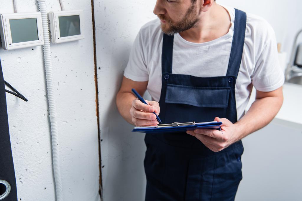 cropped image of adult electrician with clipboard checking electrical panel - Photo, Image