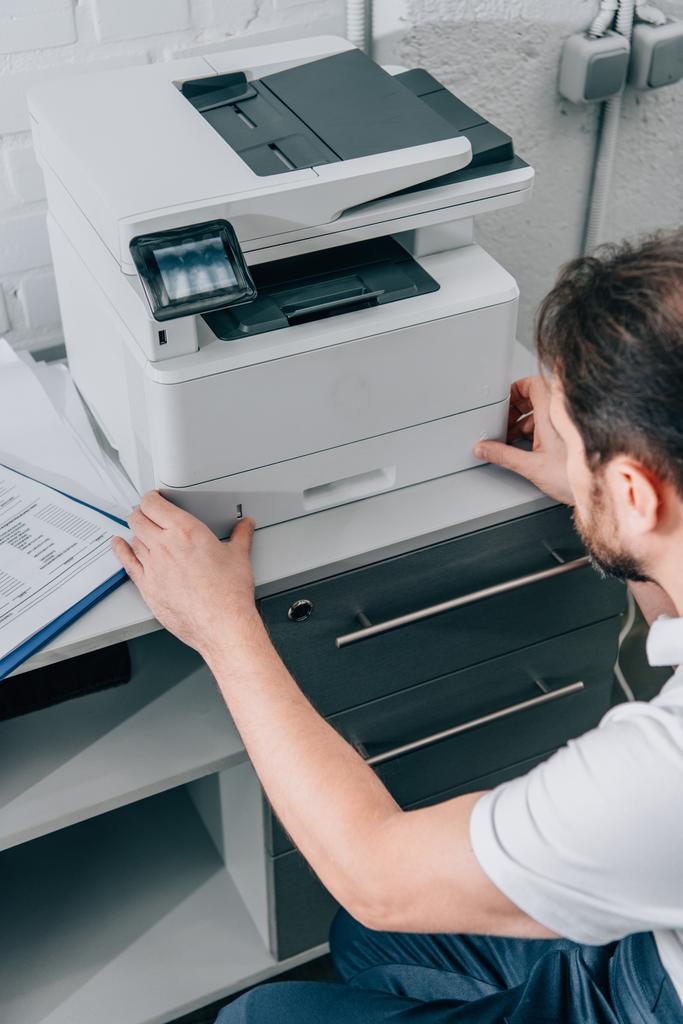 wysoki kąt widzenia faktotum mężczyzna naprawa kopiarka w nowoczesnym biurze  - Zdjęcie, obraz