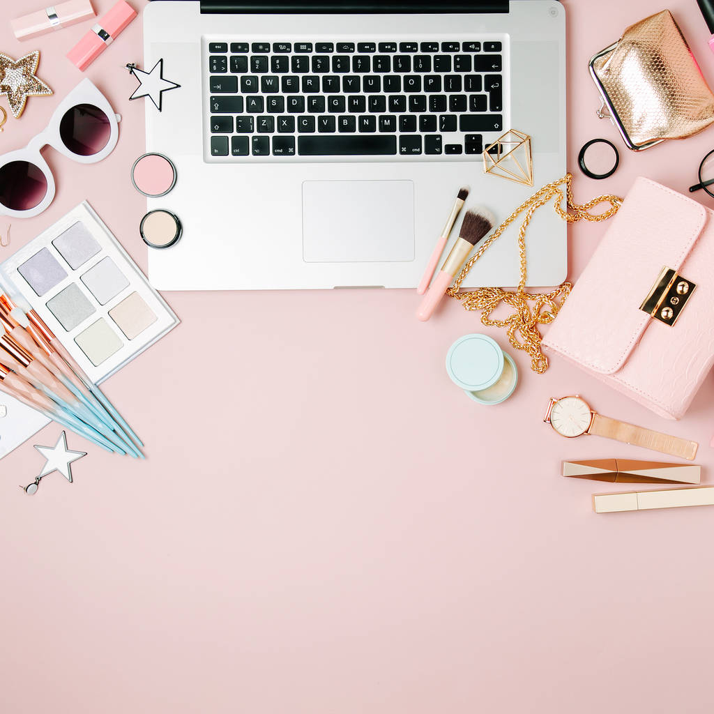 Fashion blogger werkruimte met laptop en vrouwelijke accessoire, cosmeticaproducten op bleke roze tafel. plat lag, top uitzicht - Foto, afbeelding