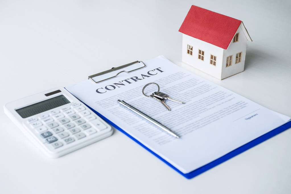 House model, calculator and house key lying on real estate contract, home loan and investment concept. - Photo, Image