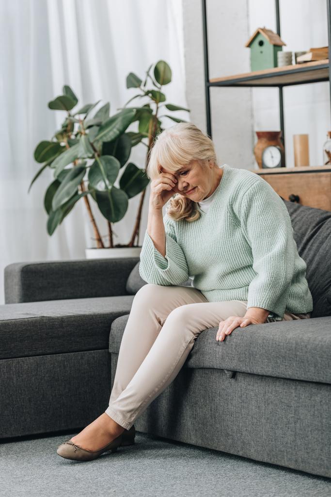 järkyttynyt eläkkeellä oleva nainen istuu sohvalla olohuoneessa
  - Valokuva, kuva