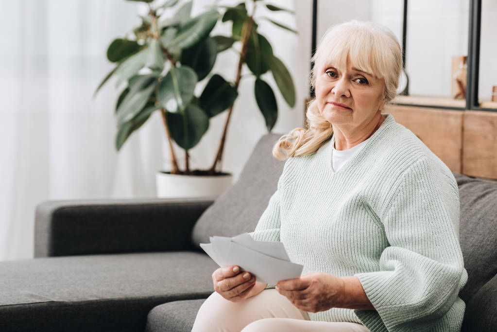sad retired woman with blonde hair holding photos - Photo, Image