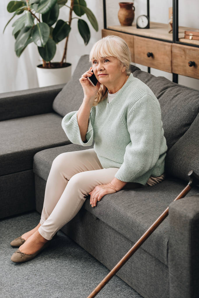 грустная пожилая женщина разговаривает на смартфоне, сидя на диване
 - Фото, изображение