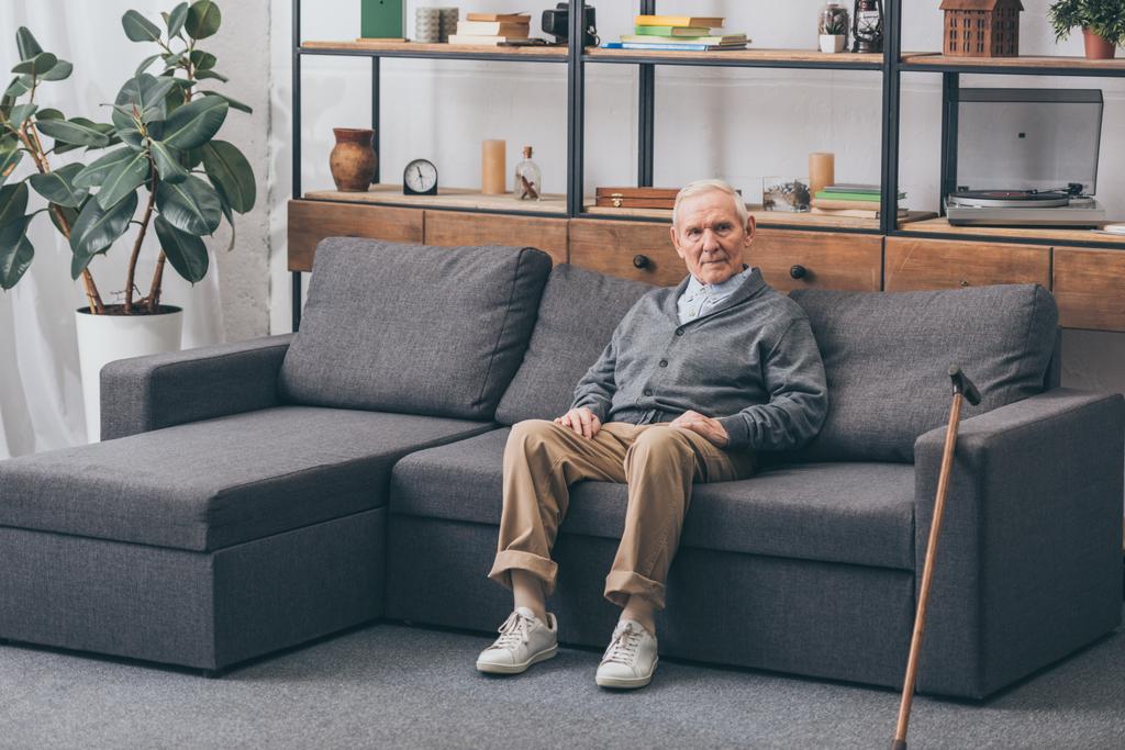 uomo anziano con capelli grigi seduto sul divano in soggiorno
  - Foto, immagini