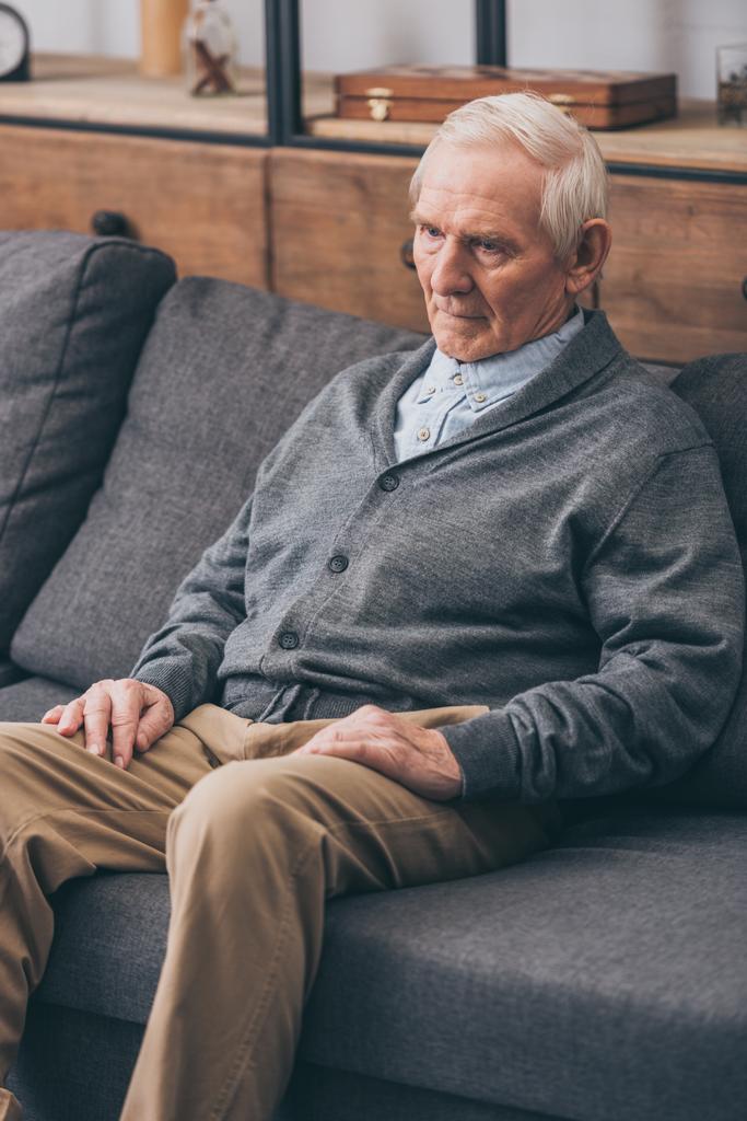 сумний старший чоловік з сірим волоссям сидить на дивані
  - Фото, зображення