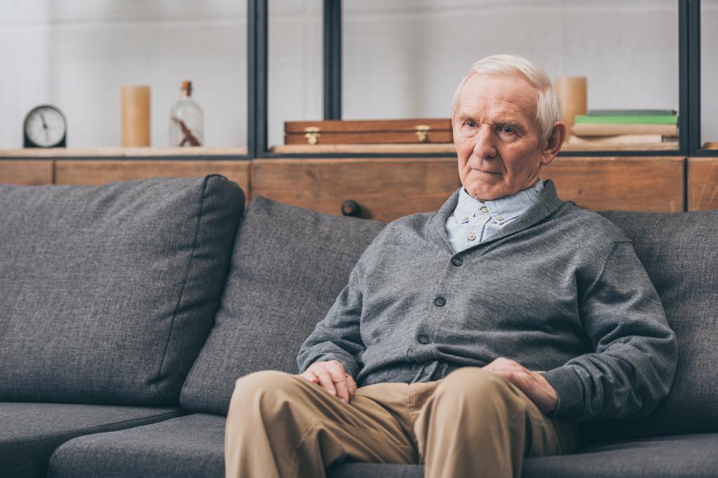homme retraité bouleversé avec les cheveux gris assis sur le canapé
  - Photo, image