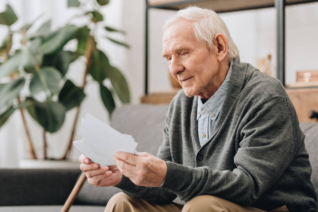 happy pensioner with grey hair looking at photos in living room - Photo, Image