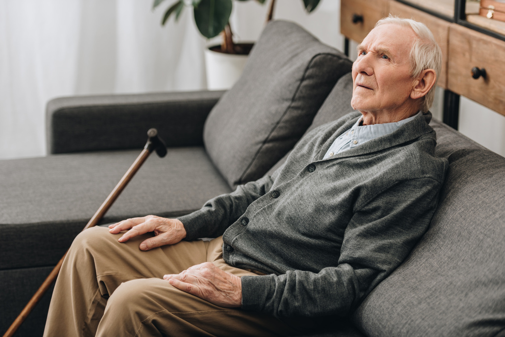 thoughtful pensioner with grey hair sitting on sofa  - Photo, Image