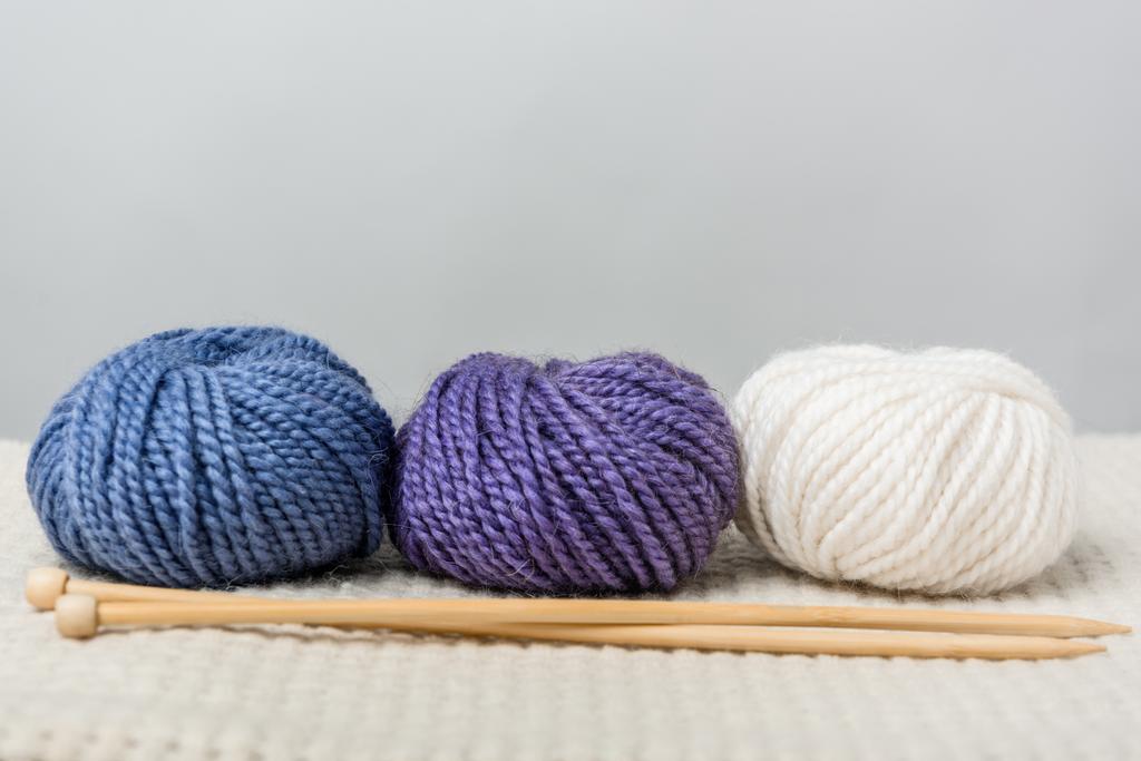 vue rapprochée des boules de fil disposées et des aiguilles à tricoter sur fond gris
 - Photo, image
