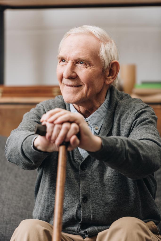 jubilado alegre sonriendo y sosteniendo bastón en casa
  - Foto, Imagen