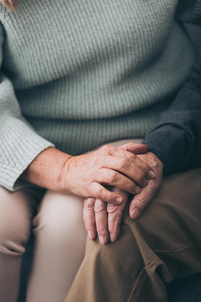 Ausgeschnittene Ansicht einer Rentnerin, die ihrem älteren Mann die Hand hält  - Foto, Bild