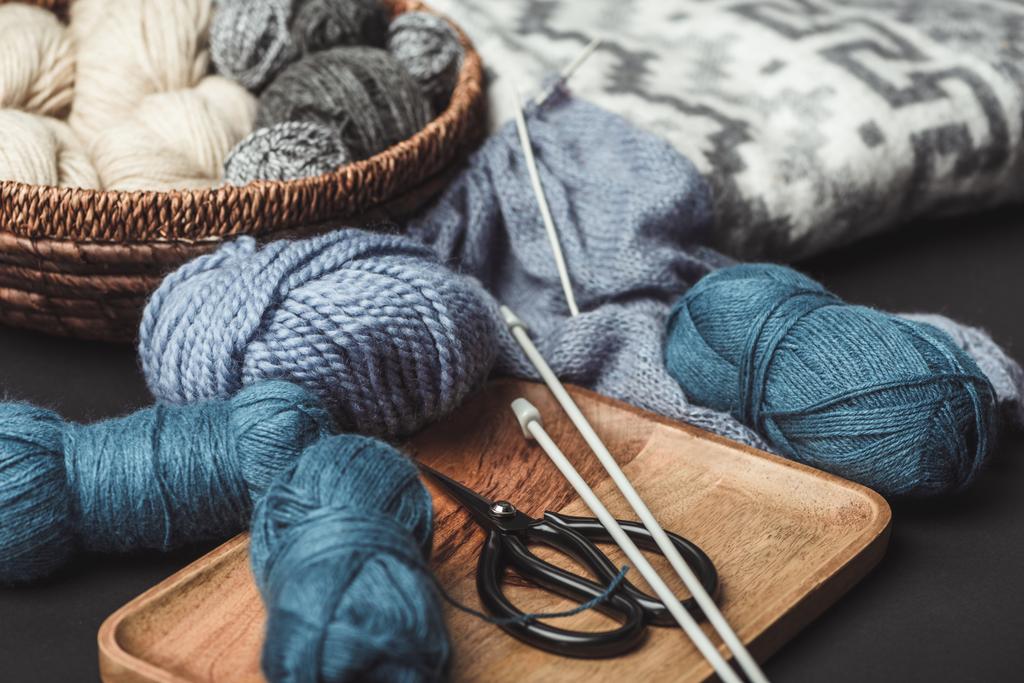 vista de perto de tricô, tesoura e agulhas de tricô em mesa escura com cobertor
 - Foto, Imagem