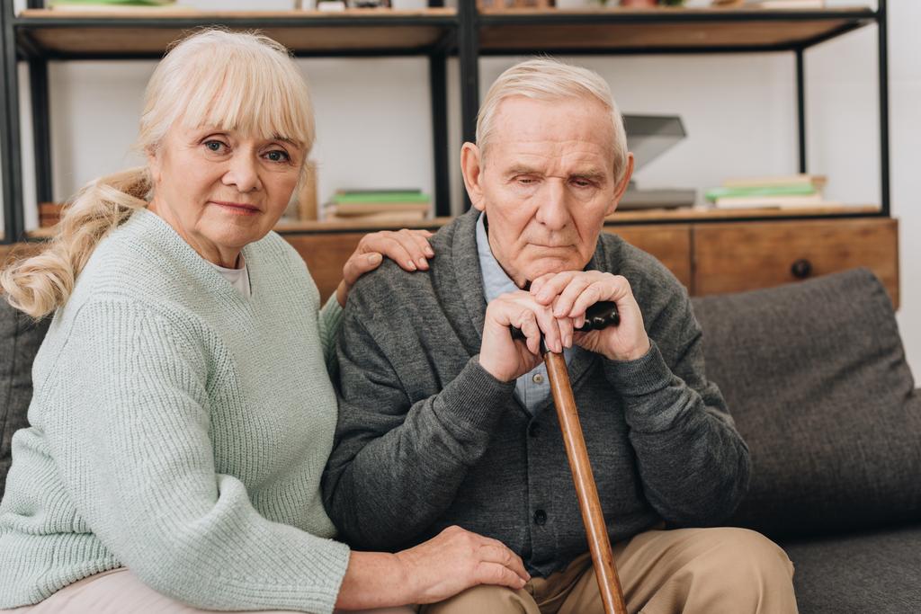 soutien femme âgée assis près de mari à la retraite avec canne à pied dans le salon
  - Photo, image