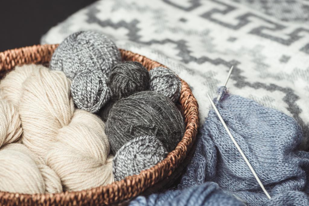 vue rapprochée des pinces à tricoter dans un panier en osier avec couverture grise sur fond
 - Photo, image