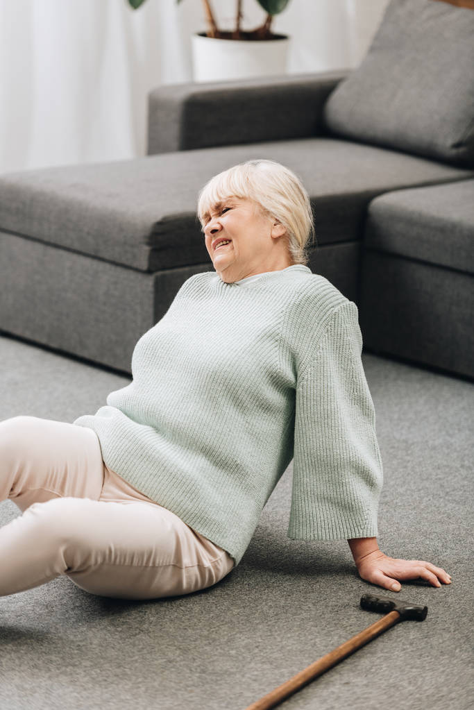 mulher aposentada com cabelo loiro sentado no chão e com dor
  - Foto, Imagem