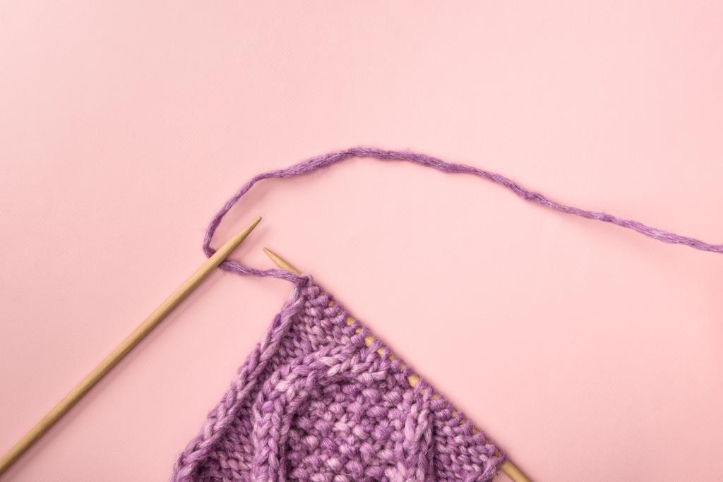 плоская постель с пурпурной пряжей и вязаными иглами на розовой поверхности
 - Фото, изображение