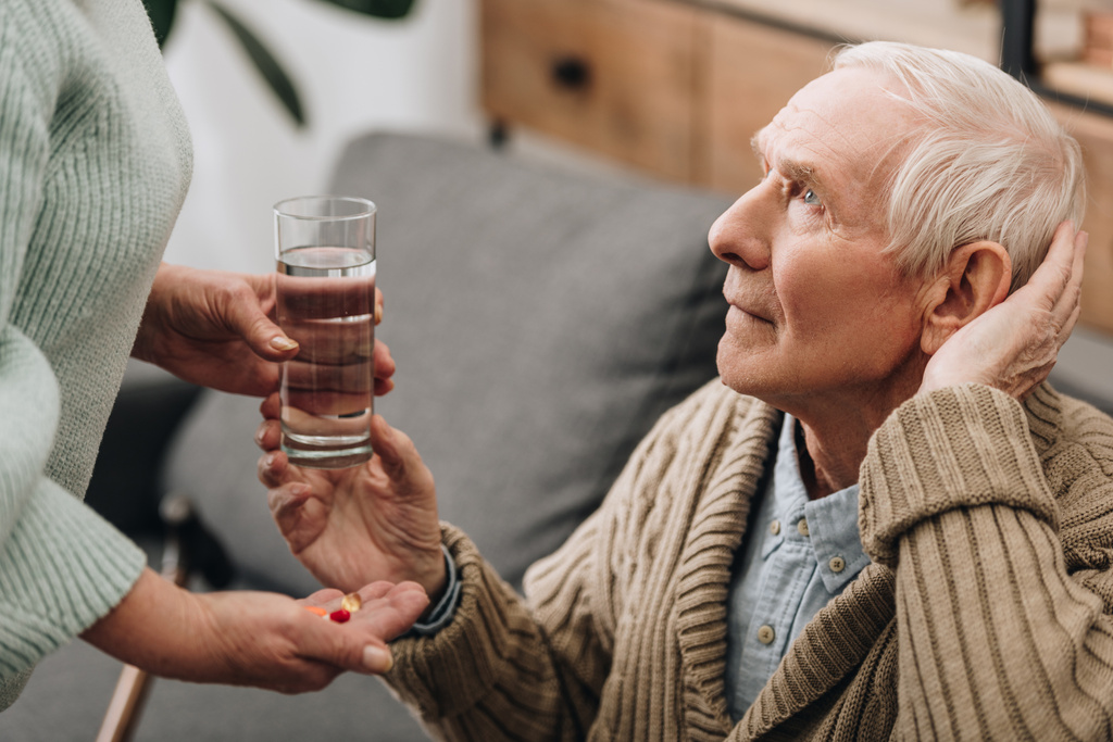 старший мужчина принимает стакан воды и таблетки от мужа
 - Фото, изображение