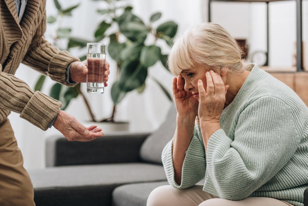 Senior gibt Glas Wasser und Pillen an alte Frau  - Foto, Bild