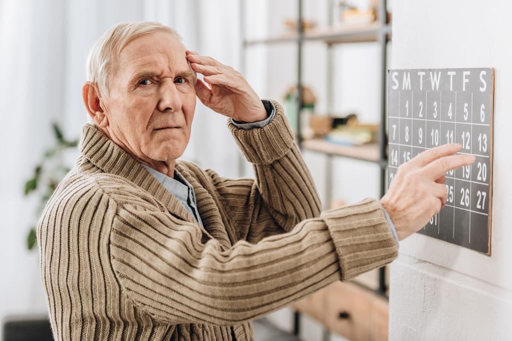 idősebb ember falinaptár és a fej rövid idő látszó-on fényképezőgép - Fotó, kép