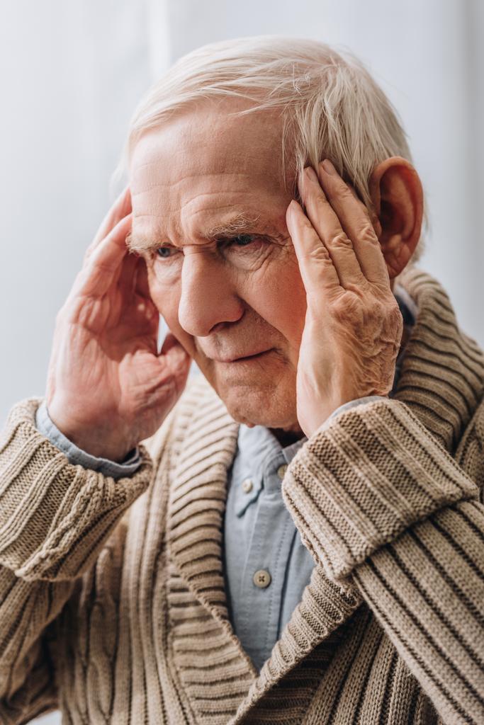 lähikuva harmaakarvaisesta eläkeläisestä, jolla on päänsärkyä kotona
  - Valokuva, kuva