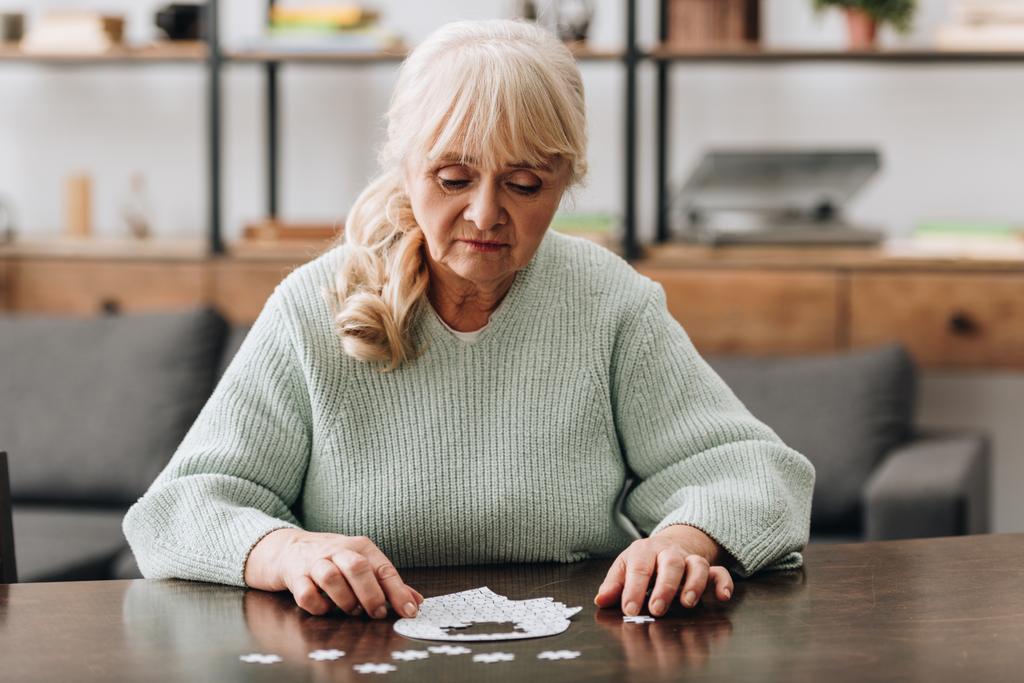 senior femme regardant des pièces de puzzle sur la table
  - Photo, image
