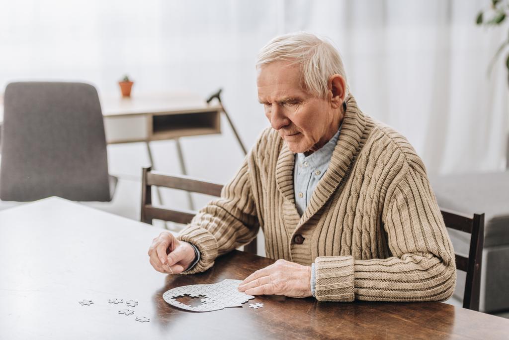 пенсіонер з сірим волоссям грає з головоломками вдома
  - Фото, зображення