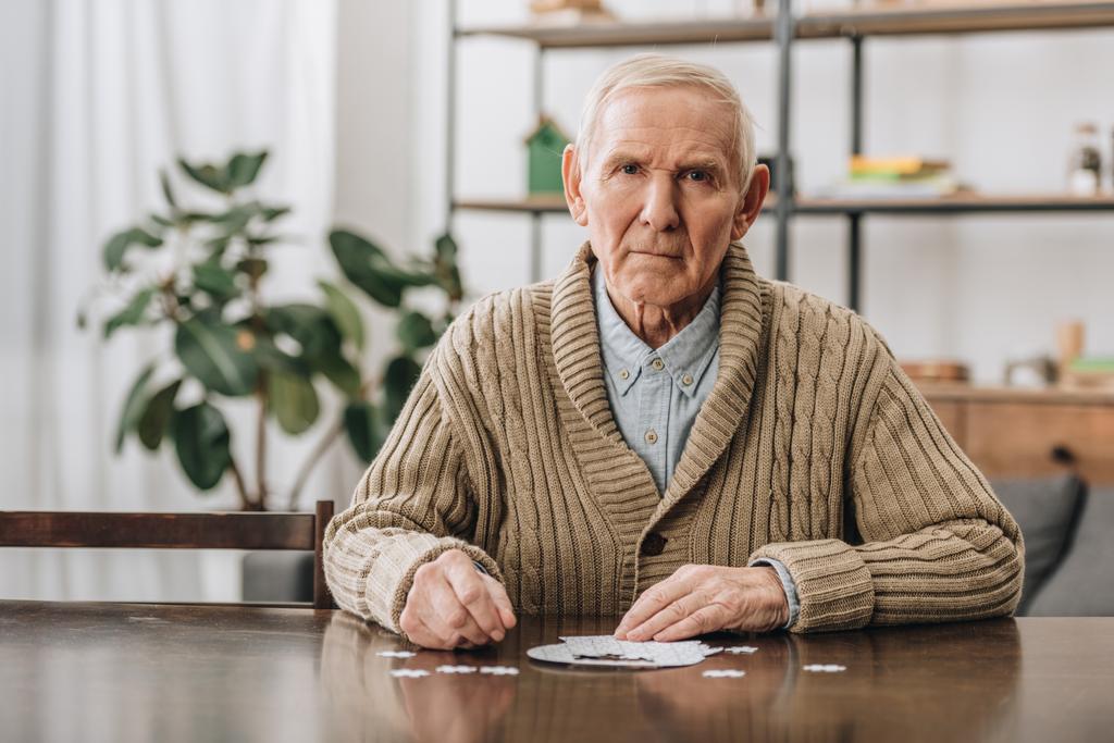 ideges nyugdíjas férfi, szürke haja, játszani rejtvények otthon  - Fotó, kép