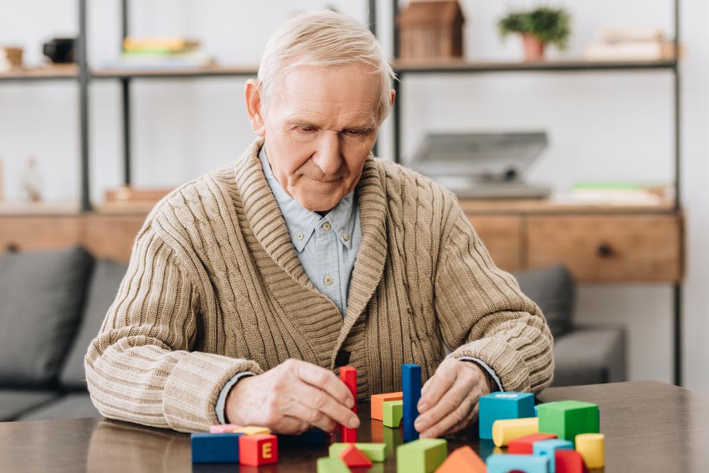 senior man playing with wooden toys at home - Photo, Image